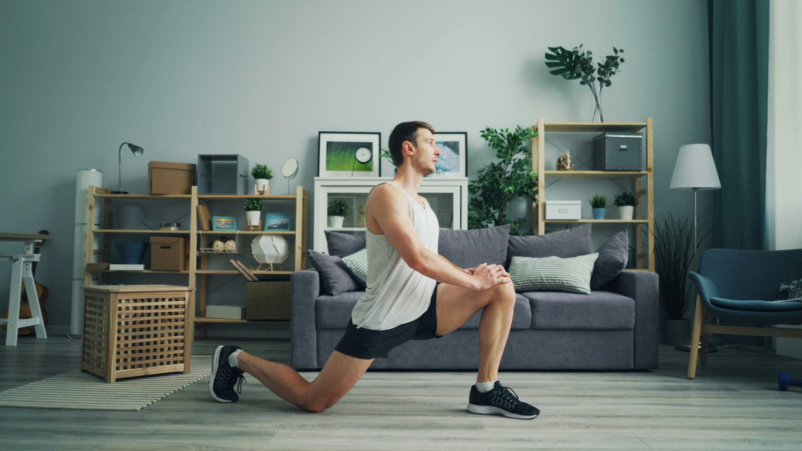 Man wearing sportswear doing lunges in a bright, modern living room environment.